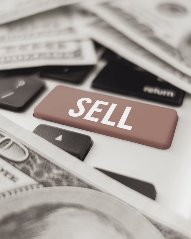 A keyboard key marked Sell, surrounded by banknotes